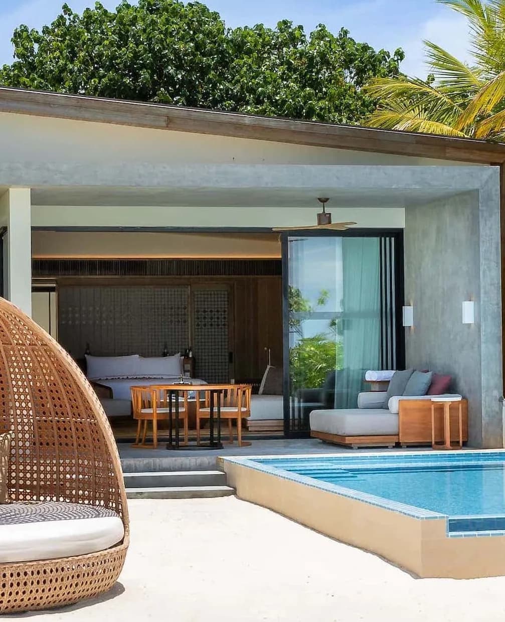 Photograph of a beach villa at MFAR Kuda Villingili Resort: an open-plan bedroom giving onto a private plunge pool and terrace.