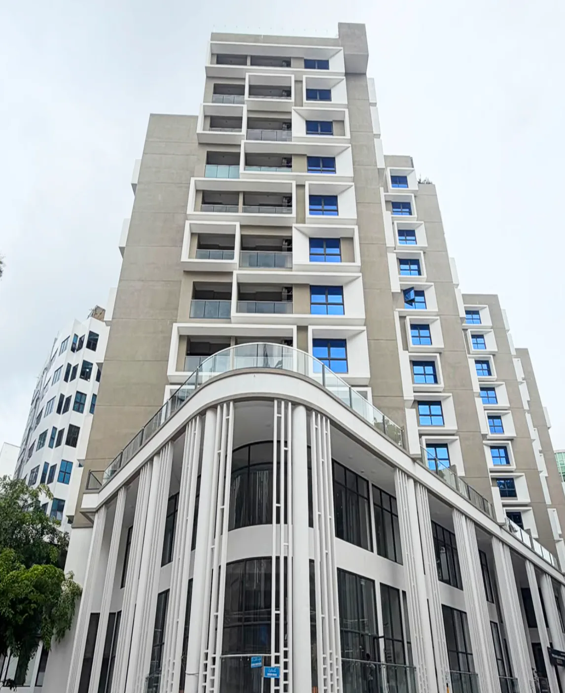 Photograph of Luxera, a residential tower on Sosun Magu, Malé, with a curved white podium and blue-glazed balconies.