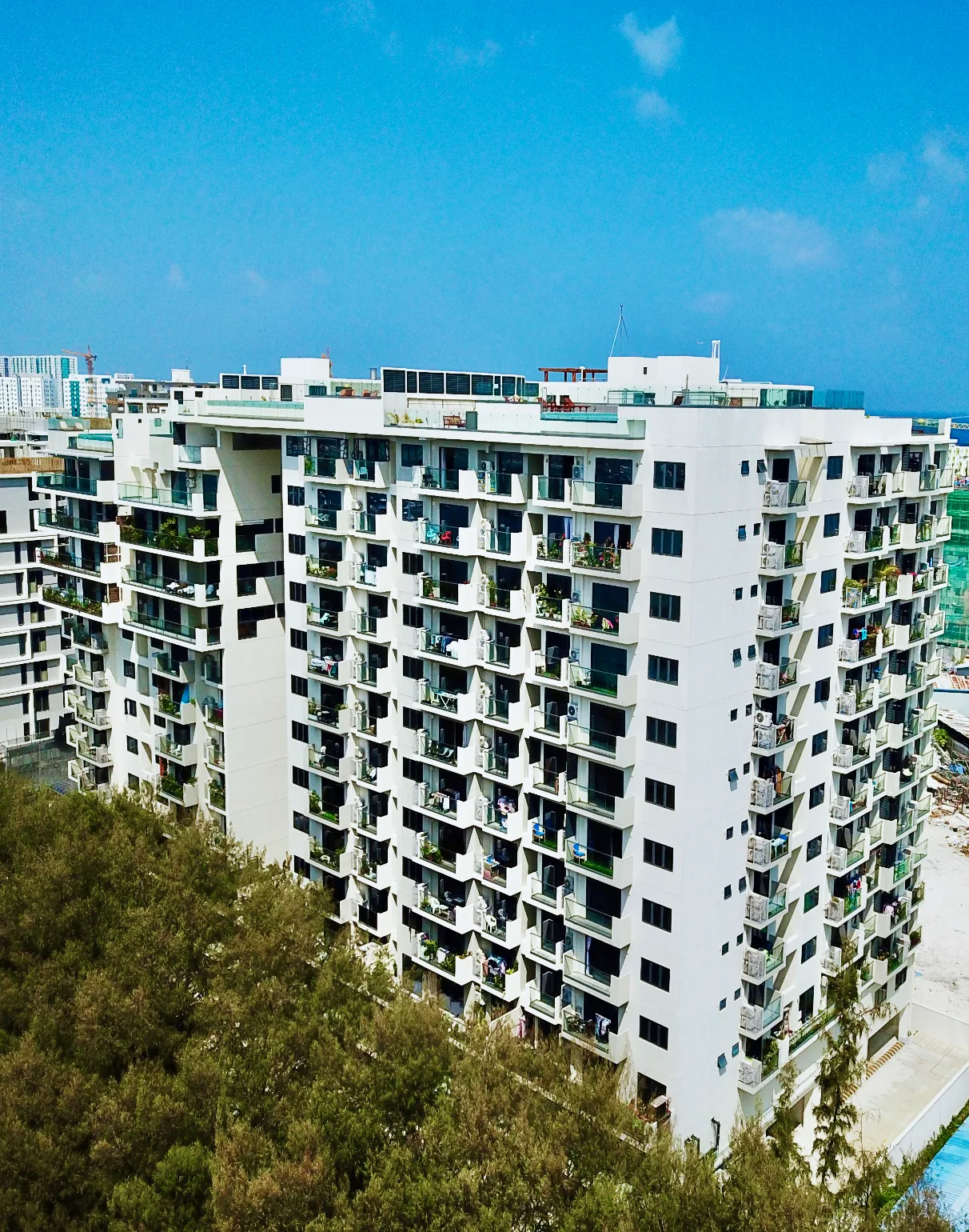 Aerial photograph of Oceanfront Residence, a white 13-storey twin-tower condominium in Hulhumalé.